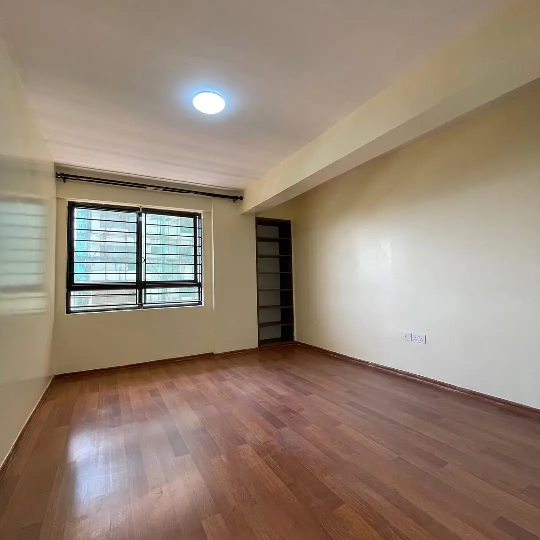 Spacious bedroom with wooden flooring and barred windows