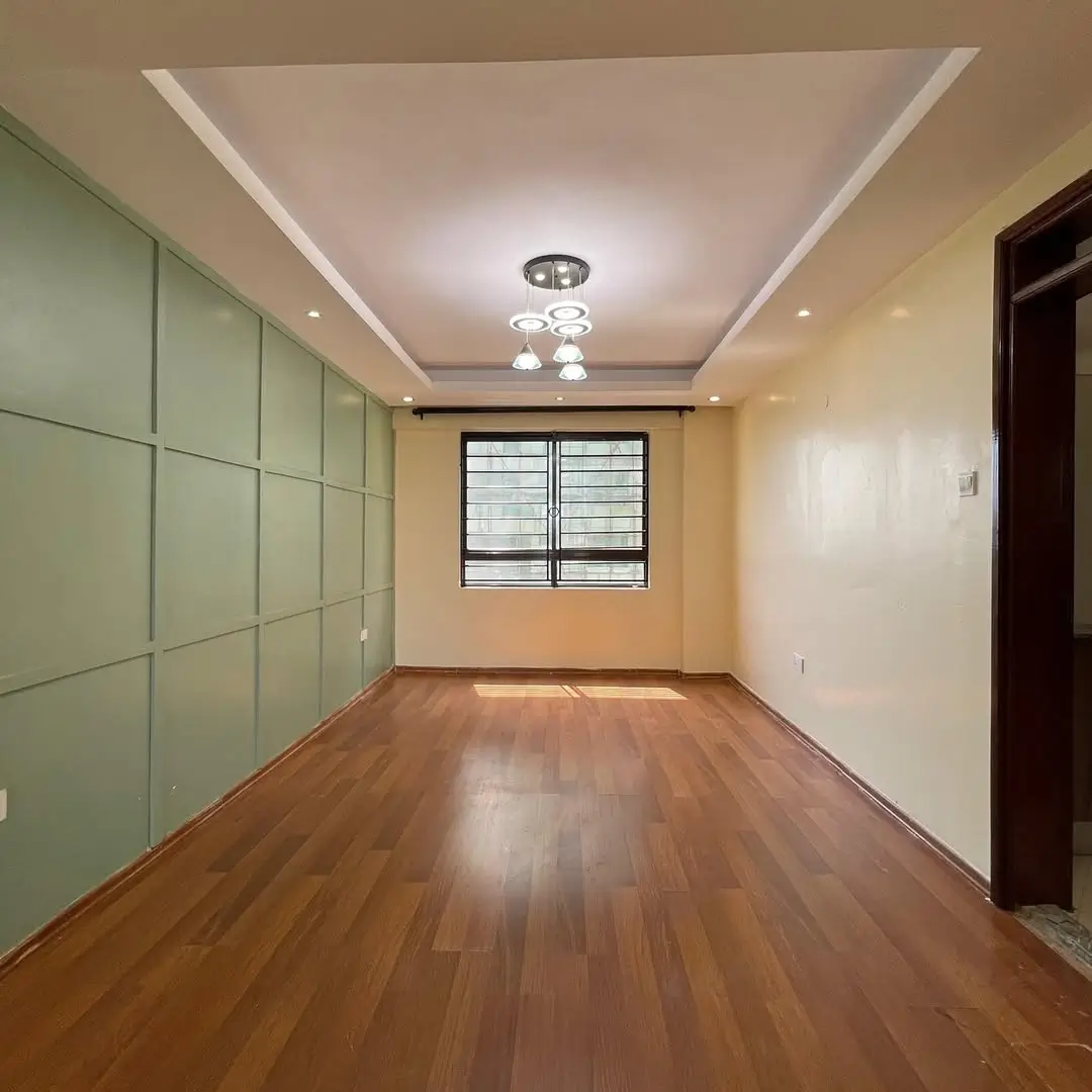 Spacious bedroom with built-in green wardrobes and wooden flooring