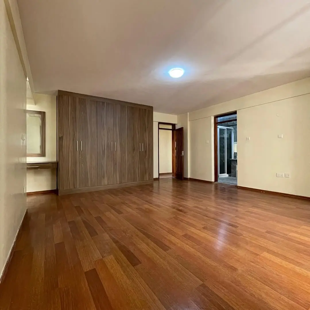Spacious bedroom with wooden wardrobe and polished wood floors