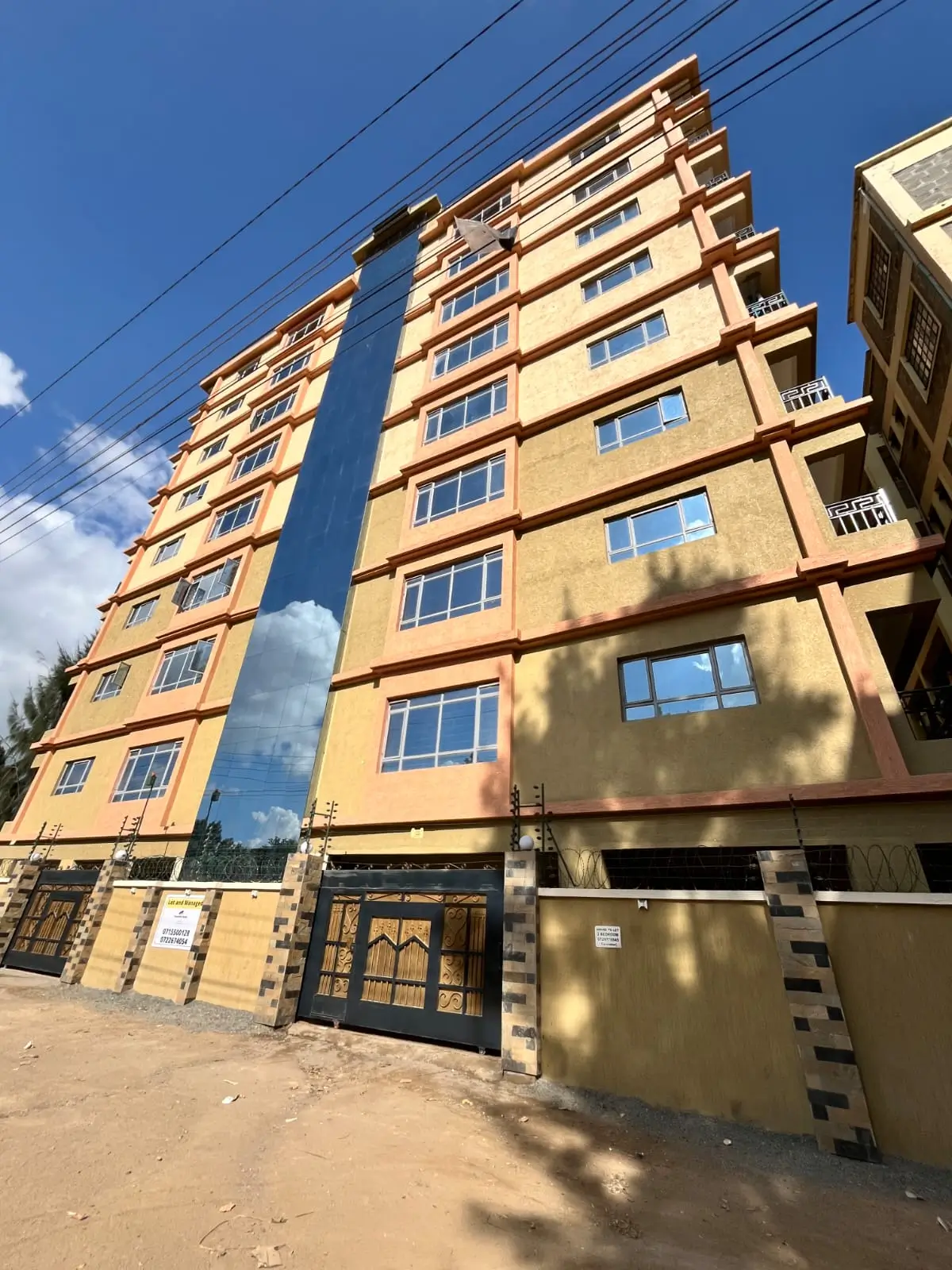 Multi-story residential building facade with yellow ochre finish