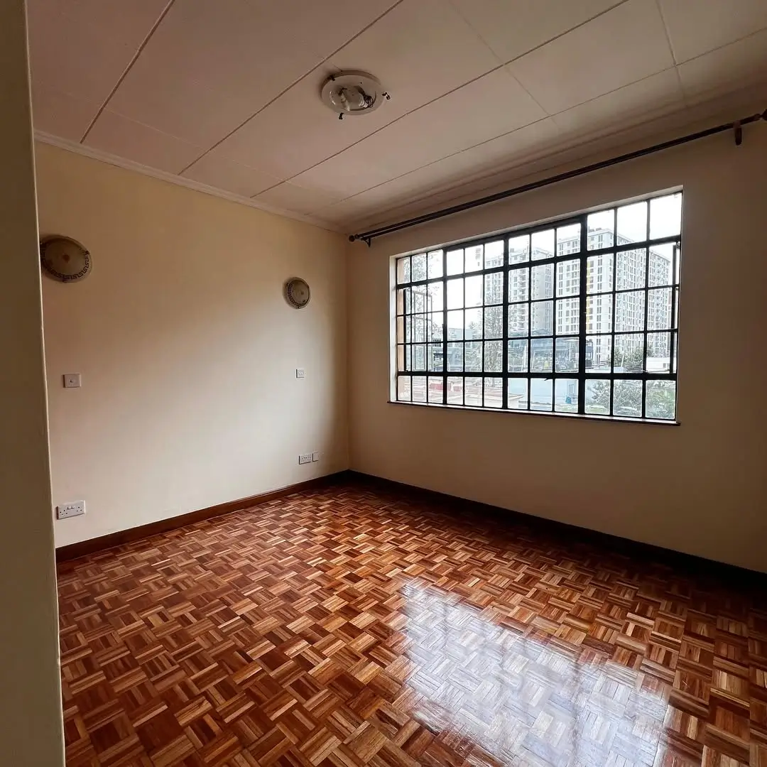 Empty bedroom with herringbone wood flooring and barred window