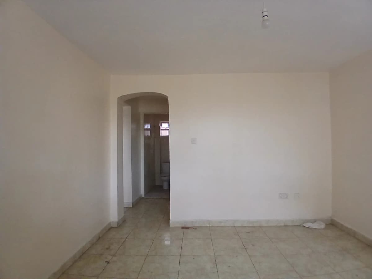 Empty living room with archway entrance and tiled flooring