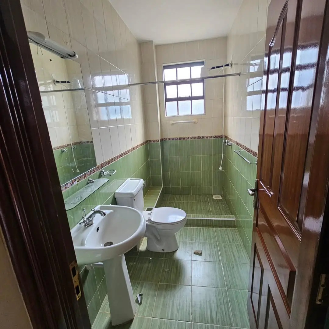 Green-tiled bathroom with pedestal sink and toilet