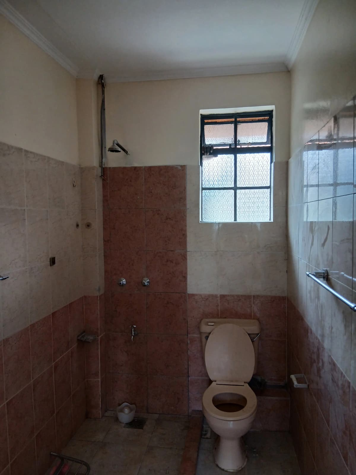 Compact bathroom with red tile accents and window