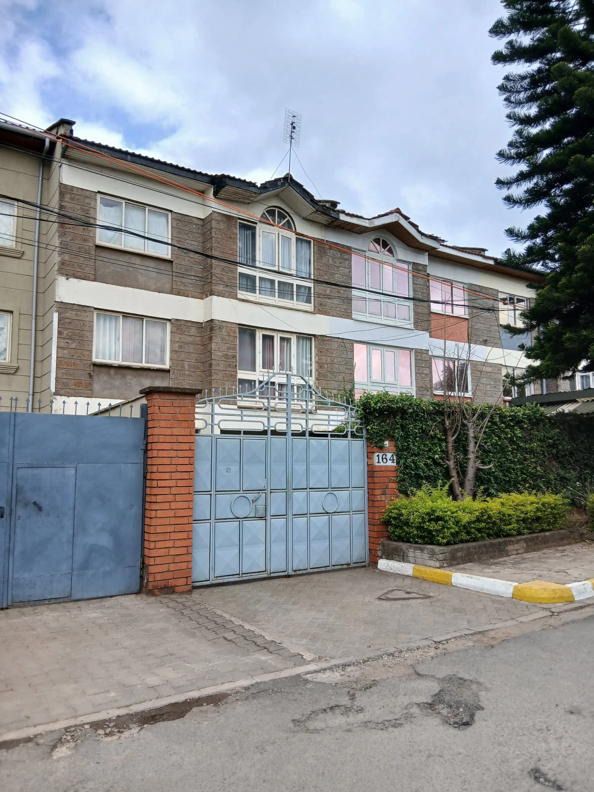 Multi-story residential building with blue gate and compound entrance