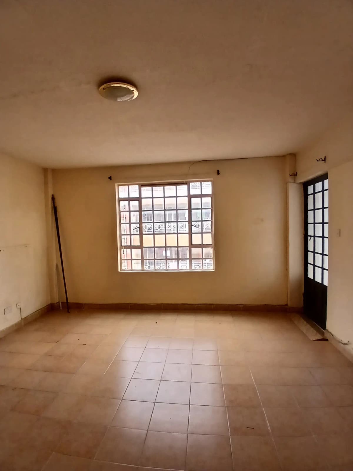 Spacious living room with large window and tiled flooring