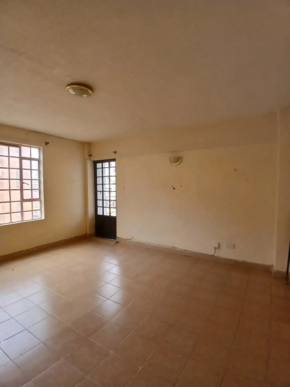 Spacious empty living room with tiled flooring and natural light