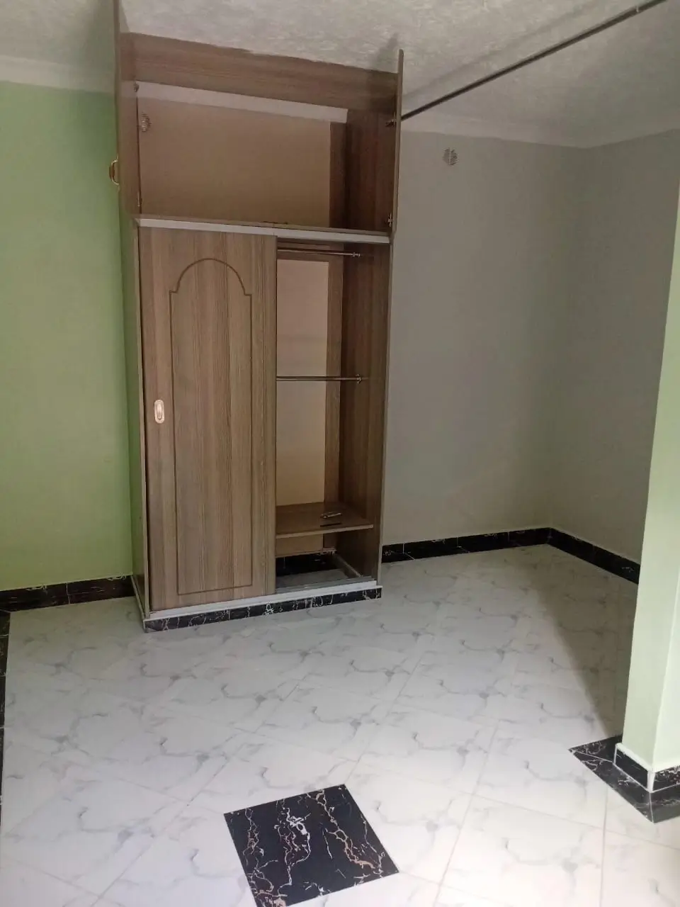 Unfurnished bedroom with wooden wardrobe and tiled flooring