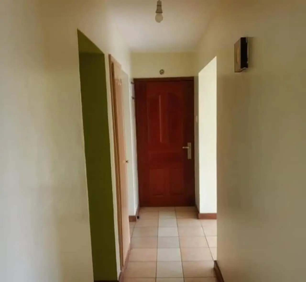Narrow hallway with cream walls and red door entry