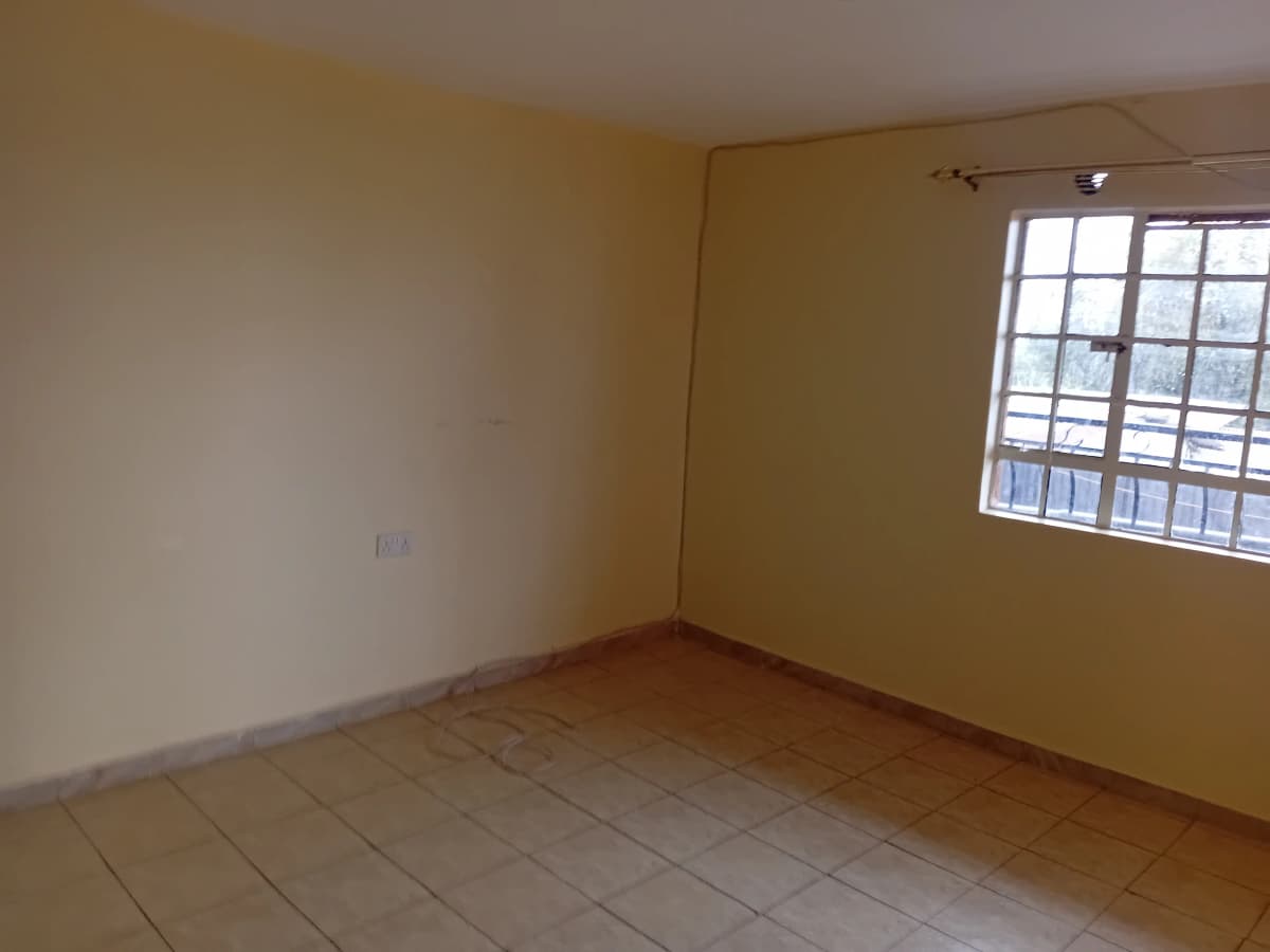 Empty bedroom with tiled floor and barred window