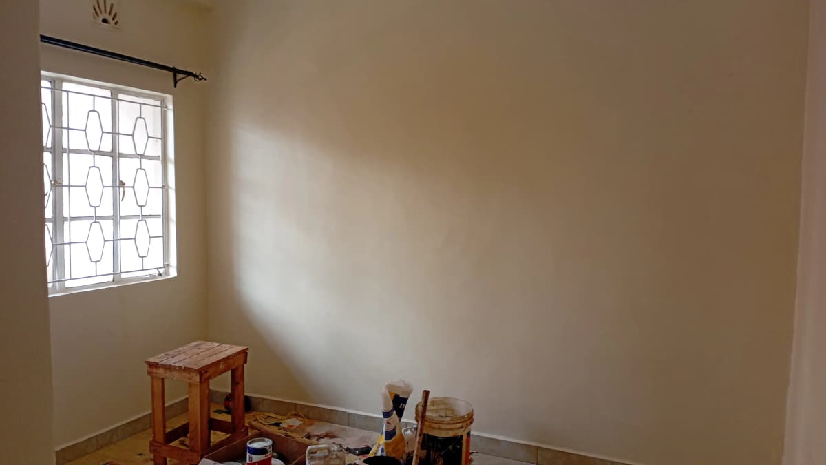 Sparse bedroom with barred window and minimal furnishings