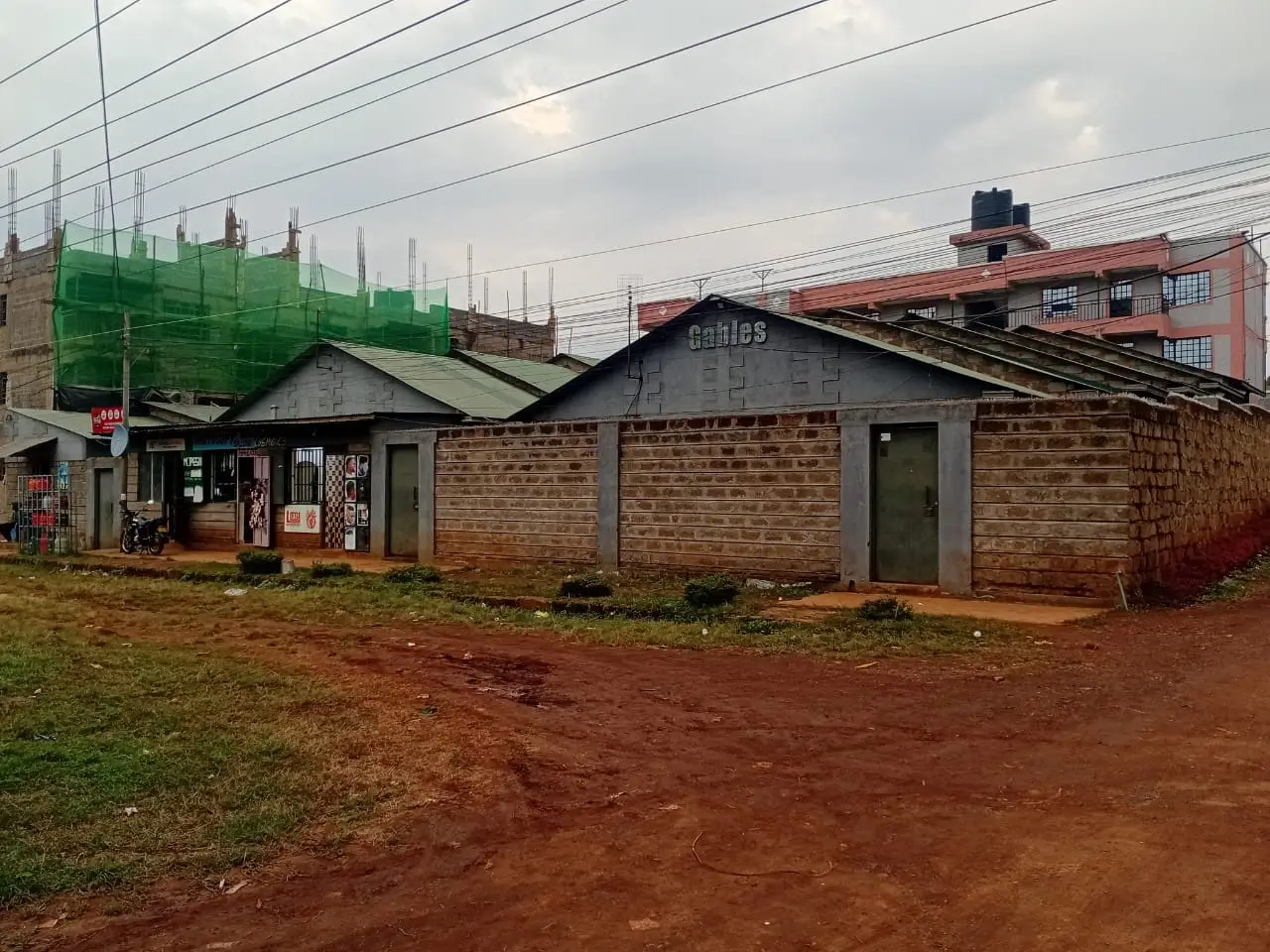 Single-story brick building with compound entrance and red soil grounds