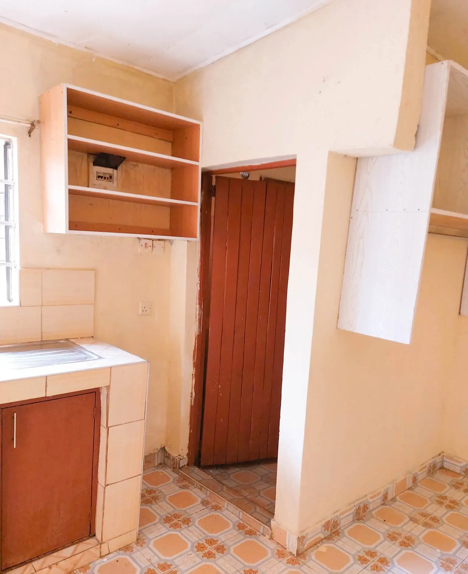 Compact kitchen with wooden cabinetry and terracotta tile floor