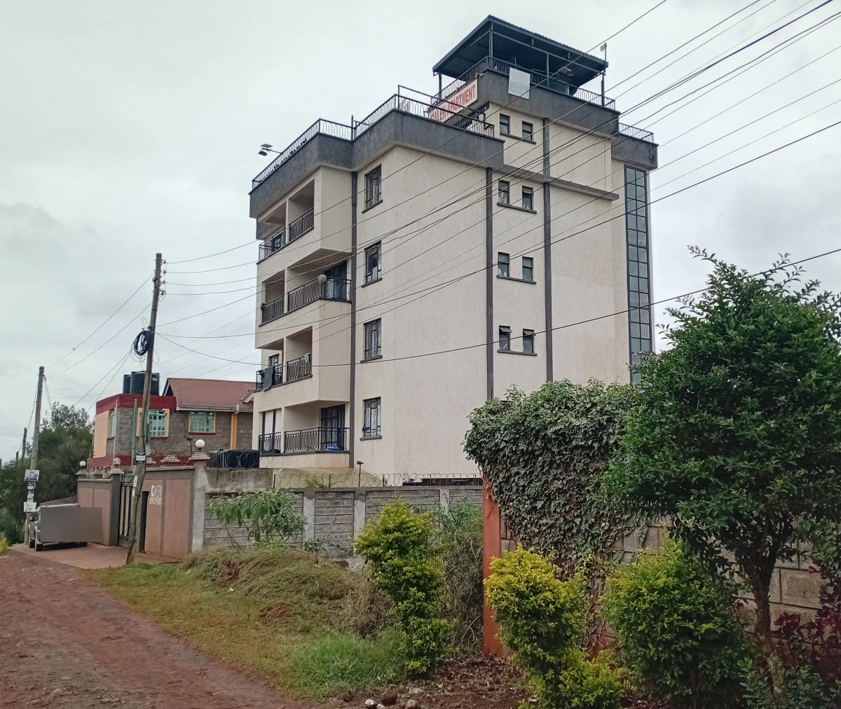 Modern multi-story residential building with balconies and compound walls