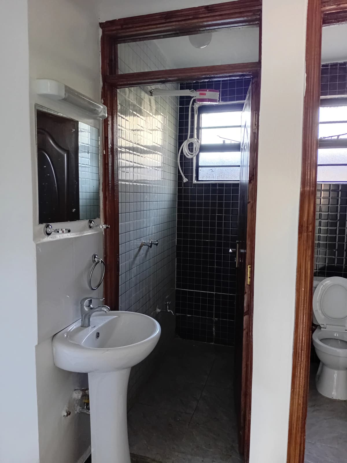 Compact bathroom with pedestal sink and black tile shower