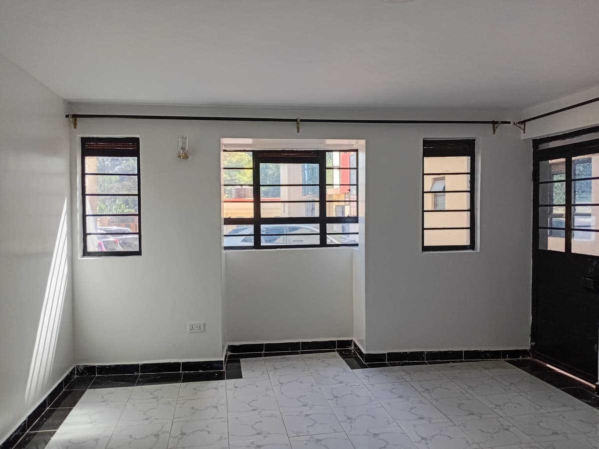 Empty living space with multiple windows and dark tile flooring