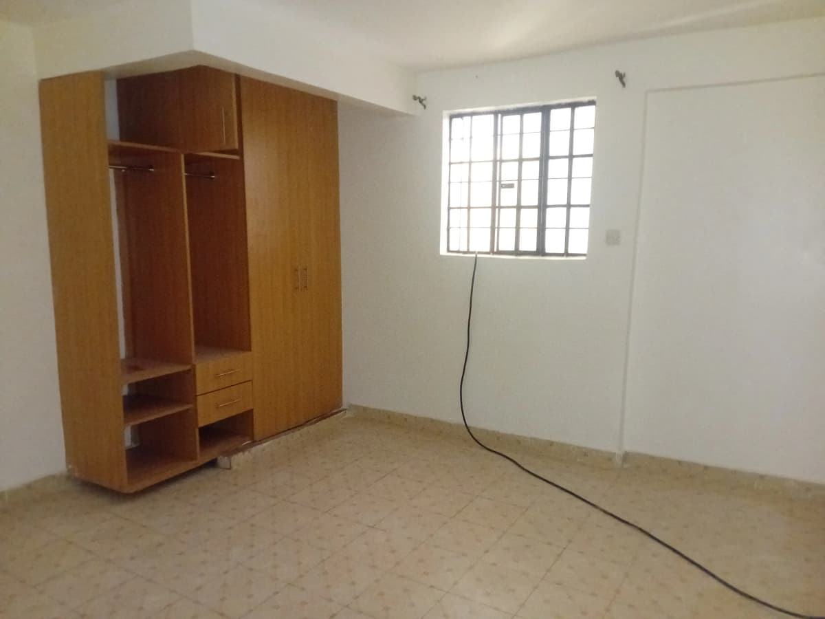 Unfurnished bedroom with wooden wardrobe and barred window