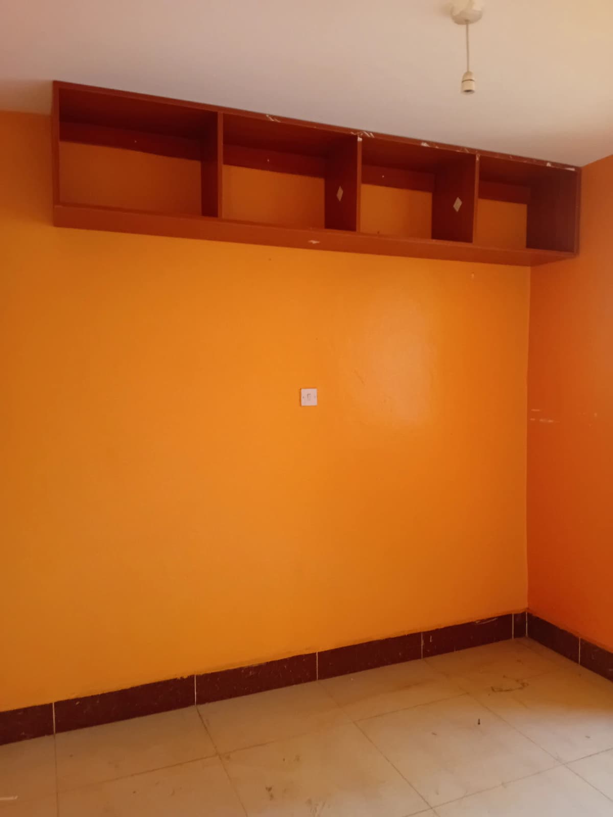 Empty bedroom with orange walls and built-in wooden shelving