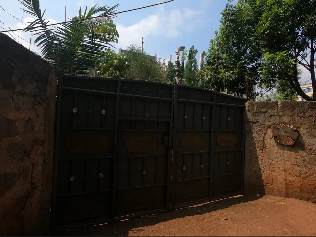 Black metal compound gate with brick perimeter walls