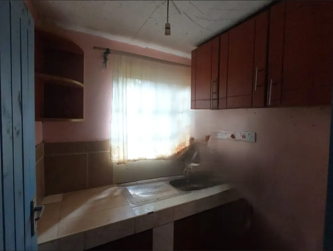 Compact kitchen with red cabinetry and natural light from window