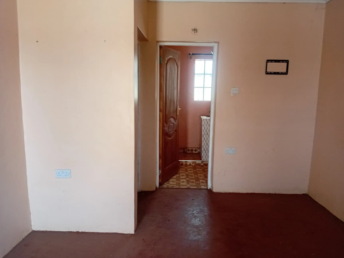 Hallway with dark flooring and warm-toned walls, doorway ahead