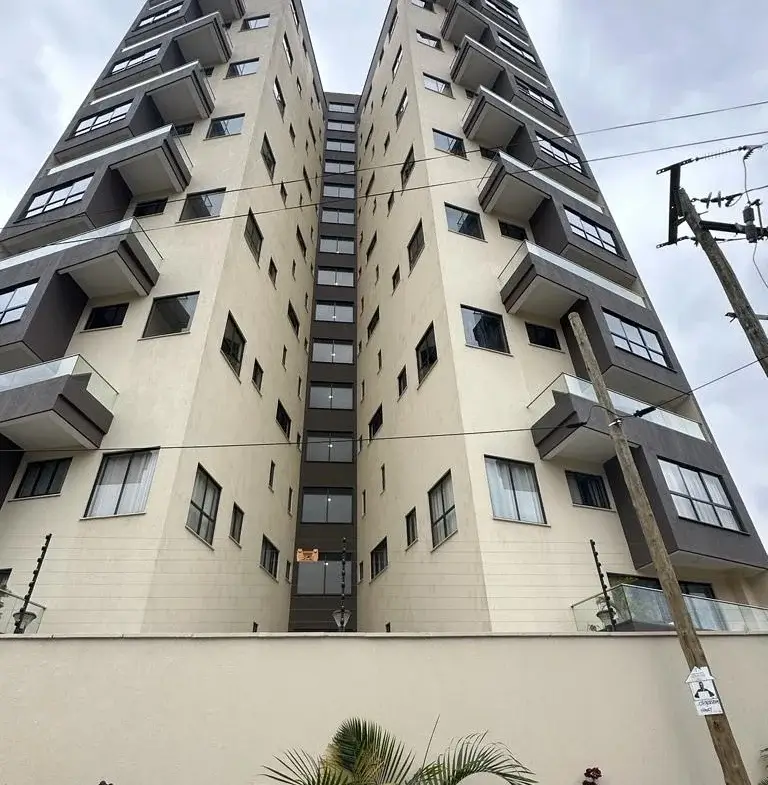 Modern multi-story residential building with balconies and compound wall