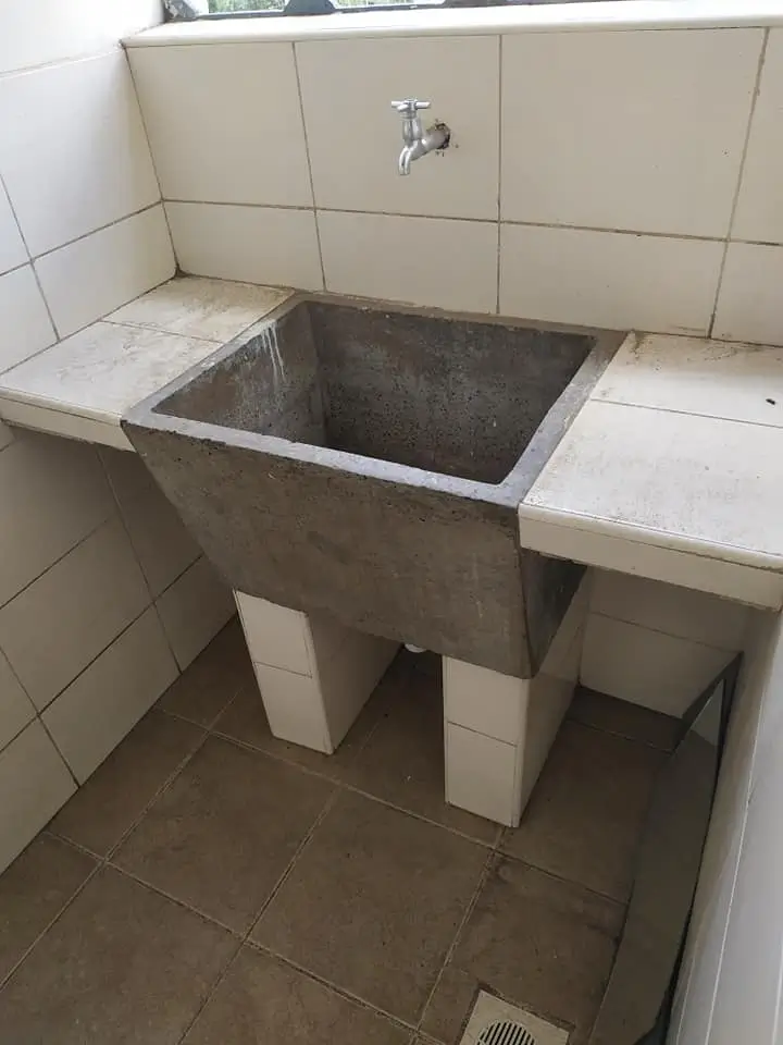 Concrete laundry sink with tap and tiled utility room