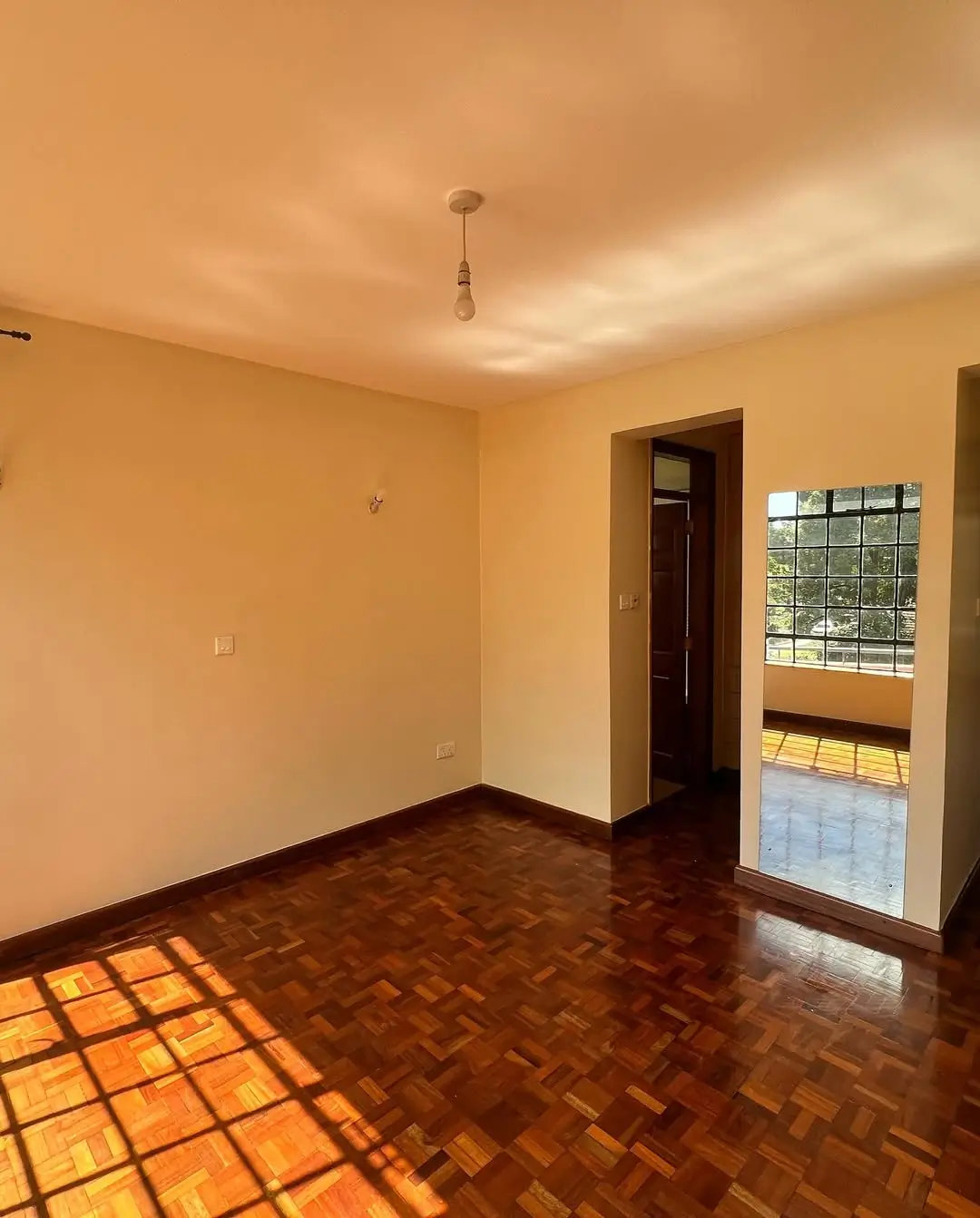 Spacious living room with herringbone parquet flooring and natural light