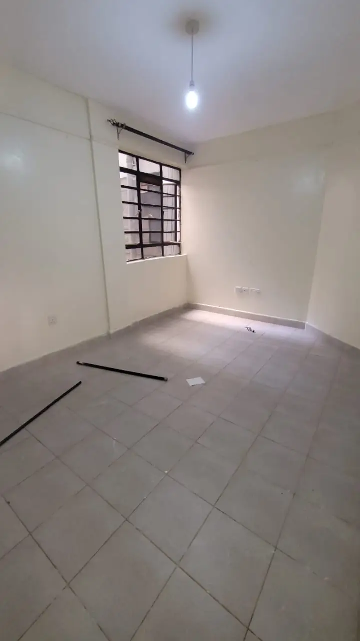 Unfurnished bedroom with barred window and tiled flooring