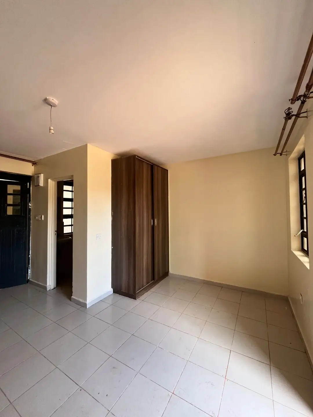 Spacious bedroom with built-in wooden wardrobe and tiled flooring