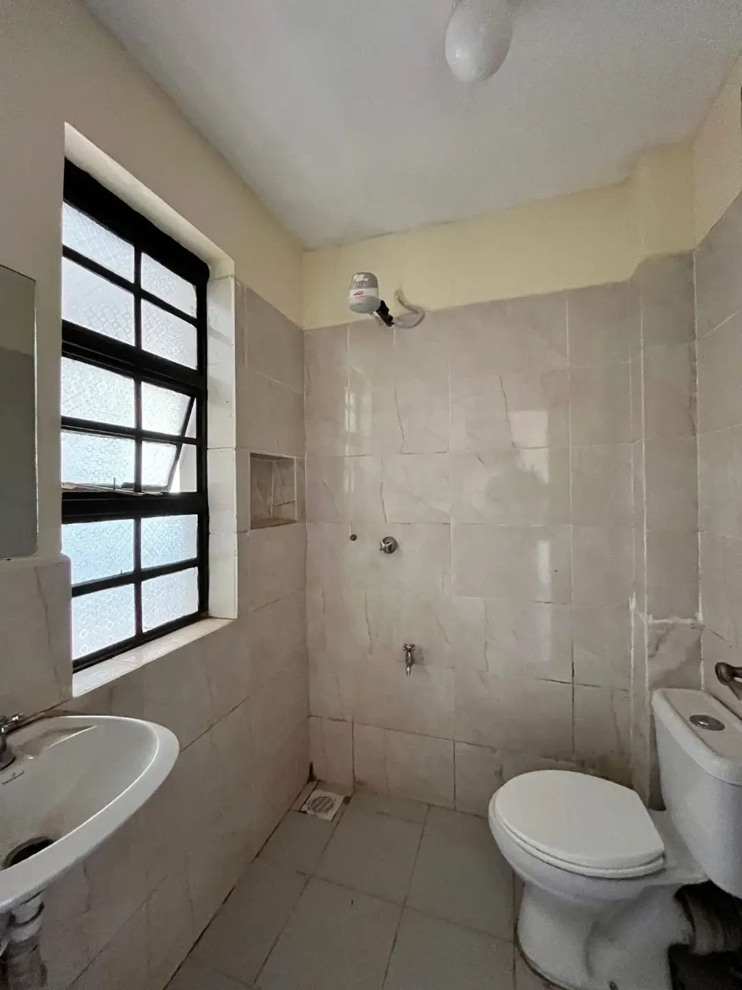 Clean bathroom with toilet, sink, shower enclosure, window