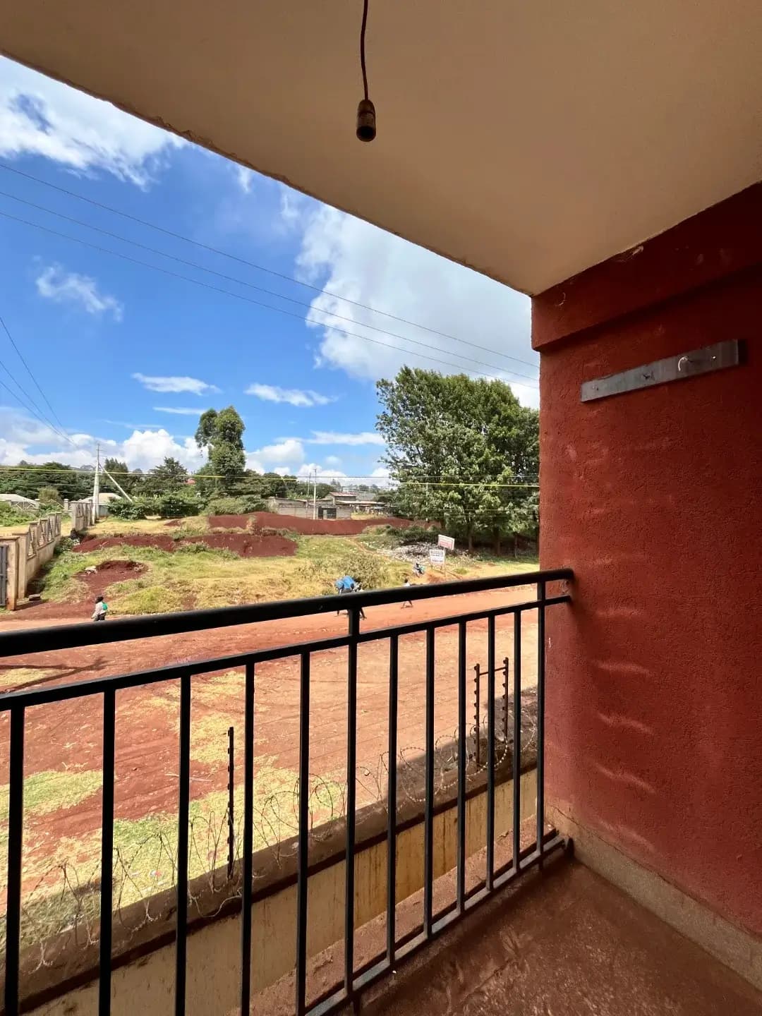 Balcony with black metal railing overlooking compound grounds