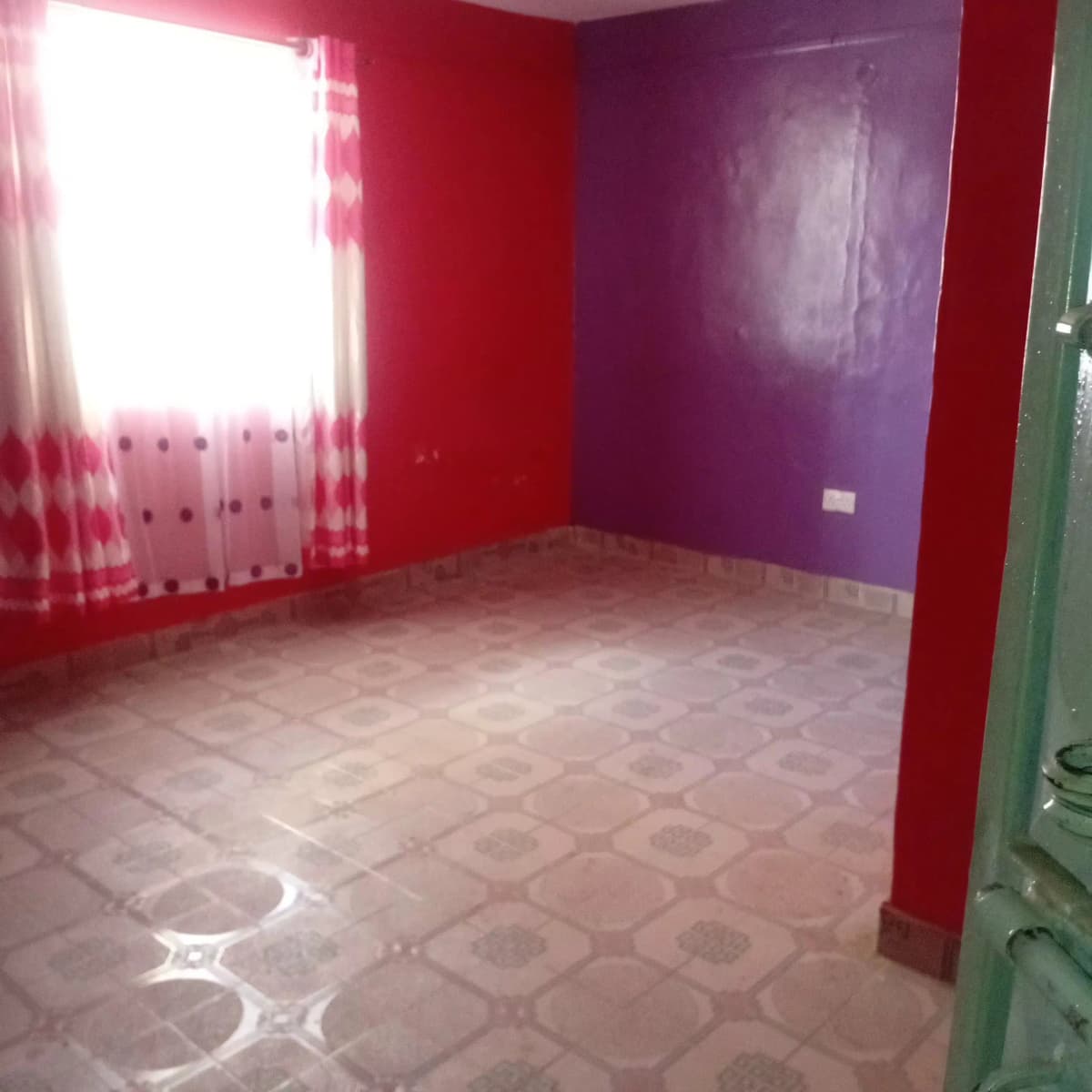Empty bedroom with bold red and purple walls, tiled floor