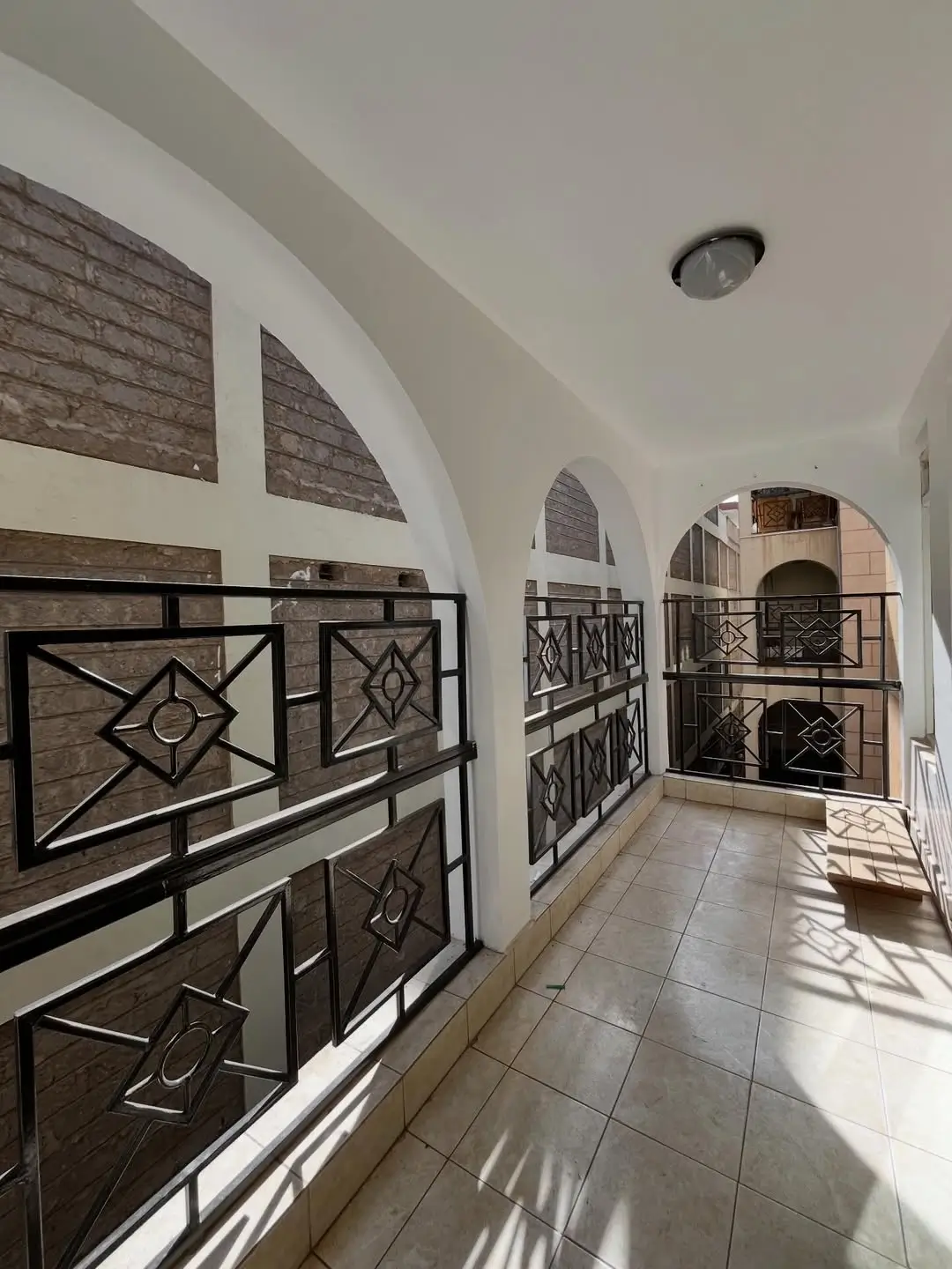 Bright corridor with decorative black railings and arched ceilings