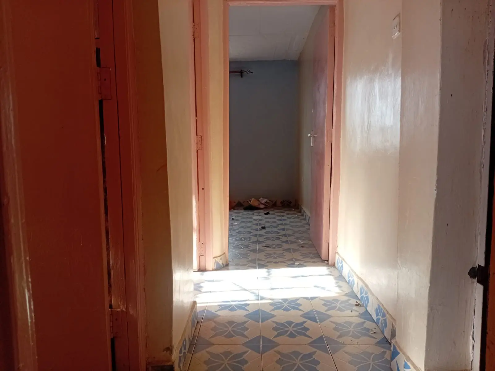 Narrow hallway with red doors and patterned tile flooring