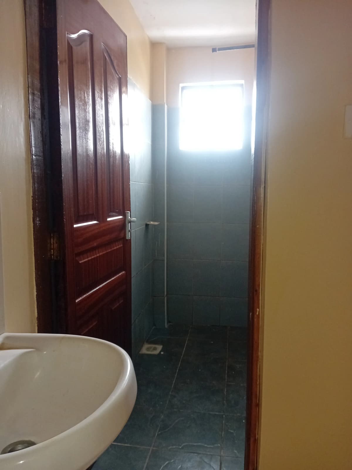 Compact bathroom with white sink and dark tile flooring