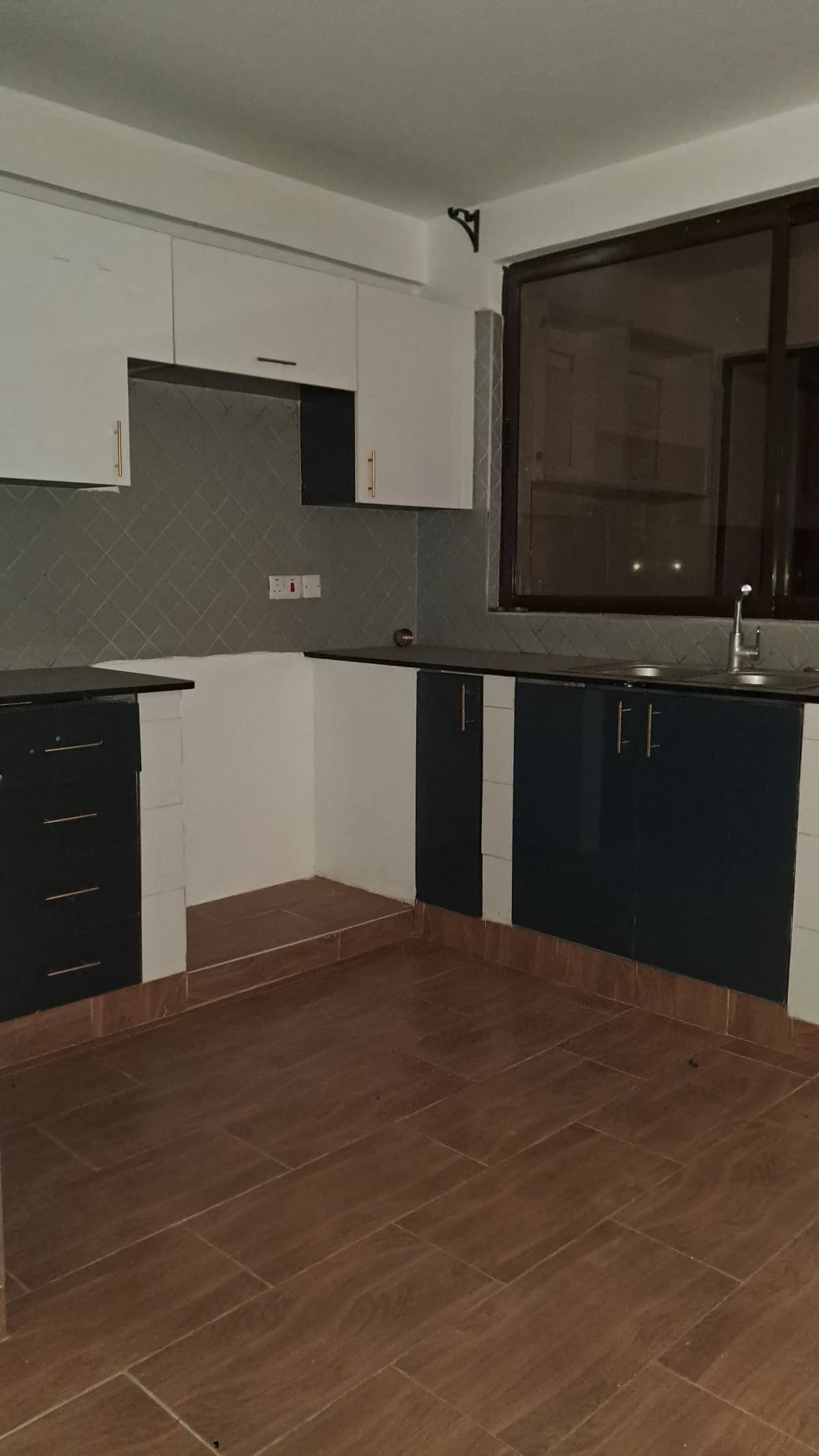 Open-plan kitchen with white upper cabinets, dark lower units, and dining floor