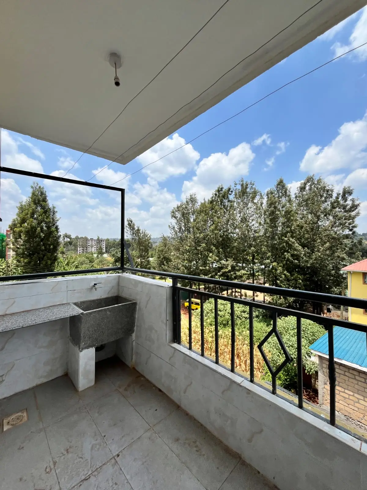 Covered balcony with concrete railings overlooking green landscape