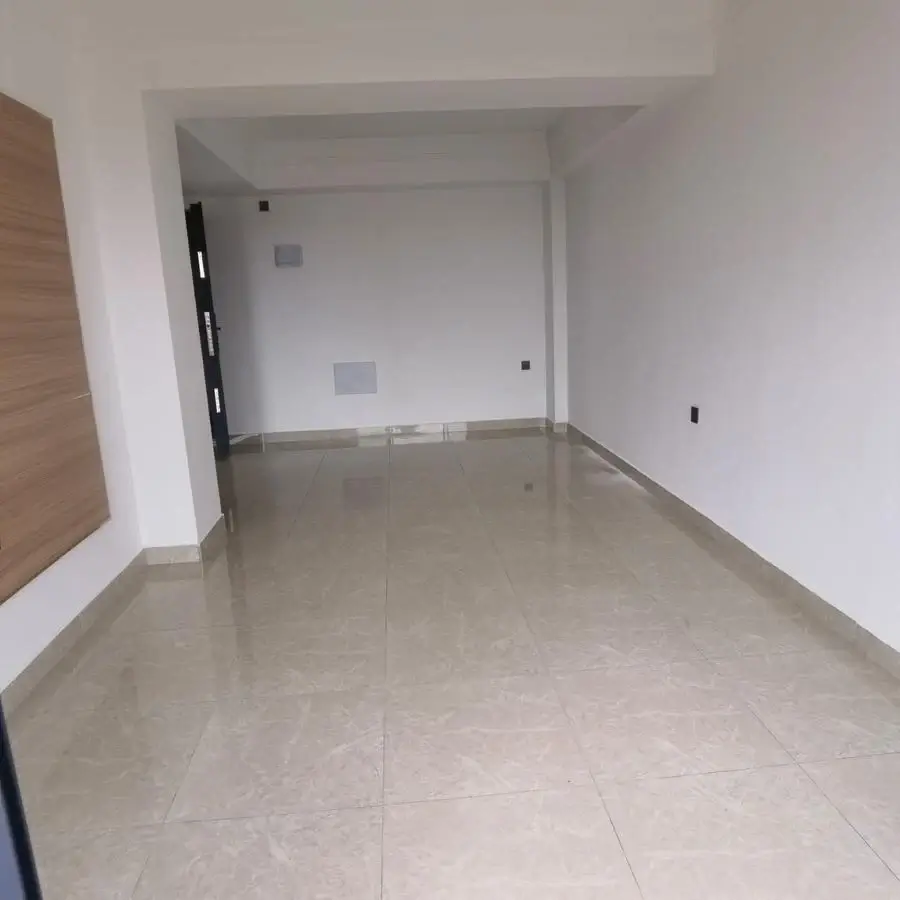 Empty living room with beige tile flooring, white walls