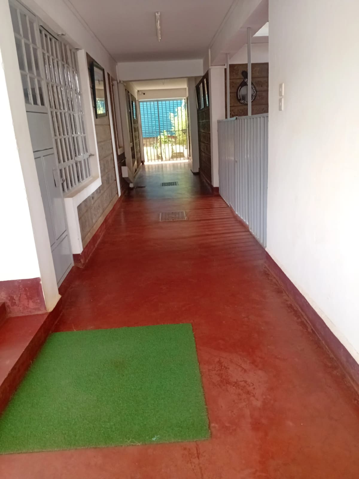 Long corridor with red flooring and bright entrance ahead