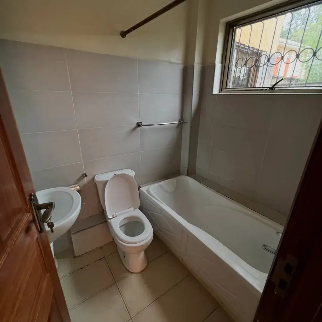 Compact bathroom with toilet, bathtub, and high window
