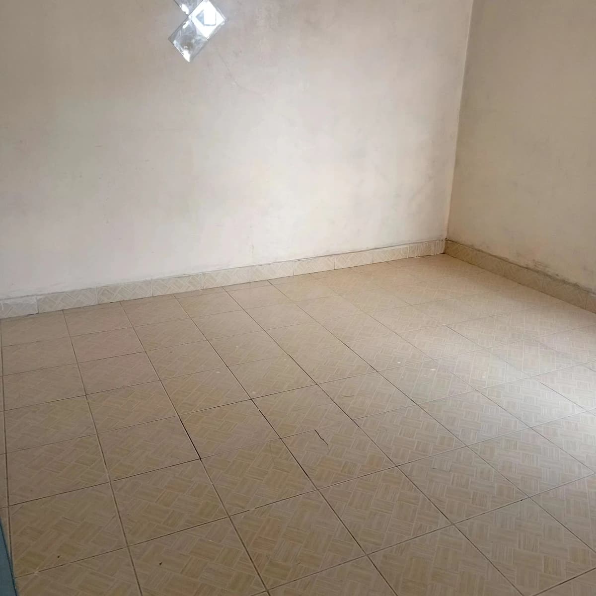 Empty room with beige tile flooring and recessed lighting