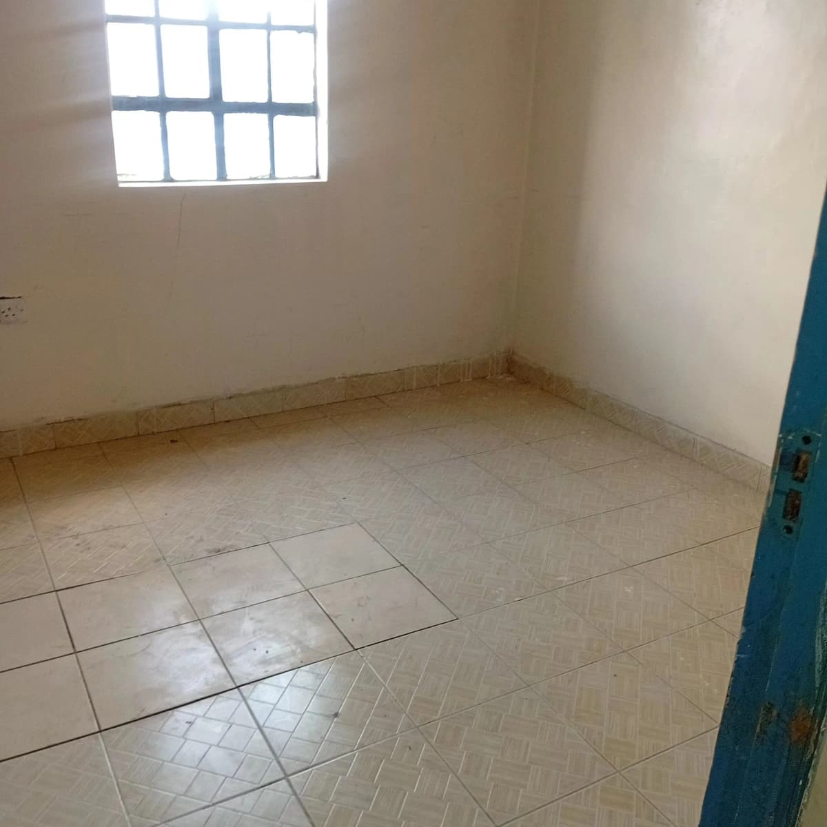 Empty bedroom with tiled floor and natural window light