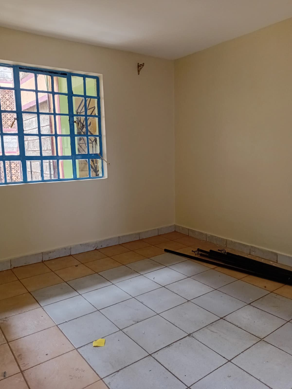 Empty bedroom with tiled floor and barred window