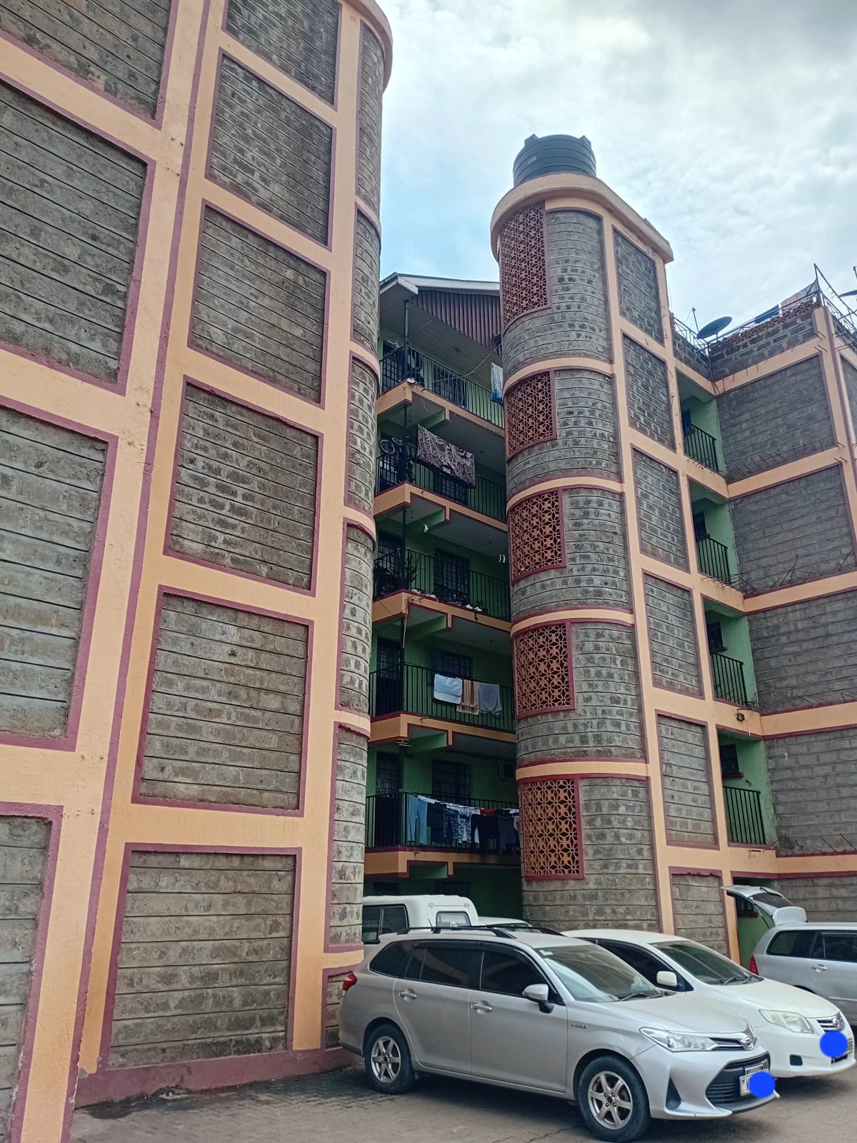Multi-story residential building with brick facade and parked cars