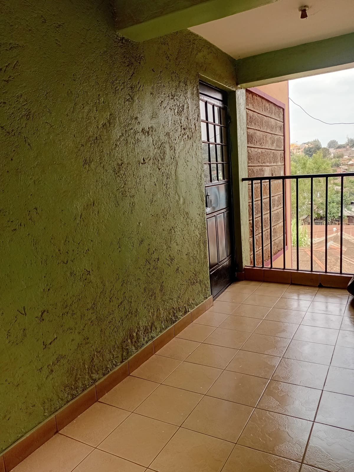 Covered balcony with textured green walls and railing