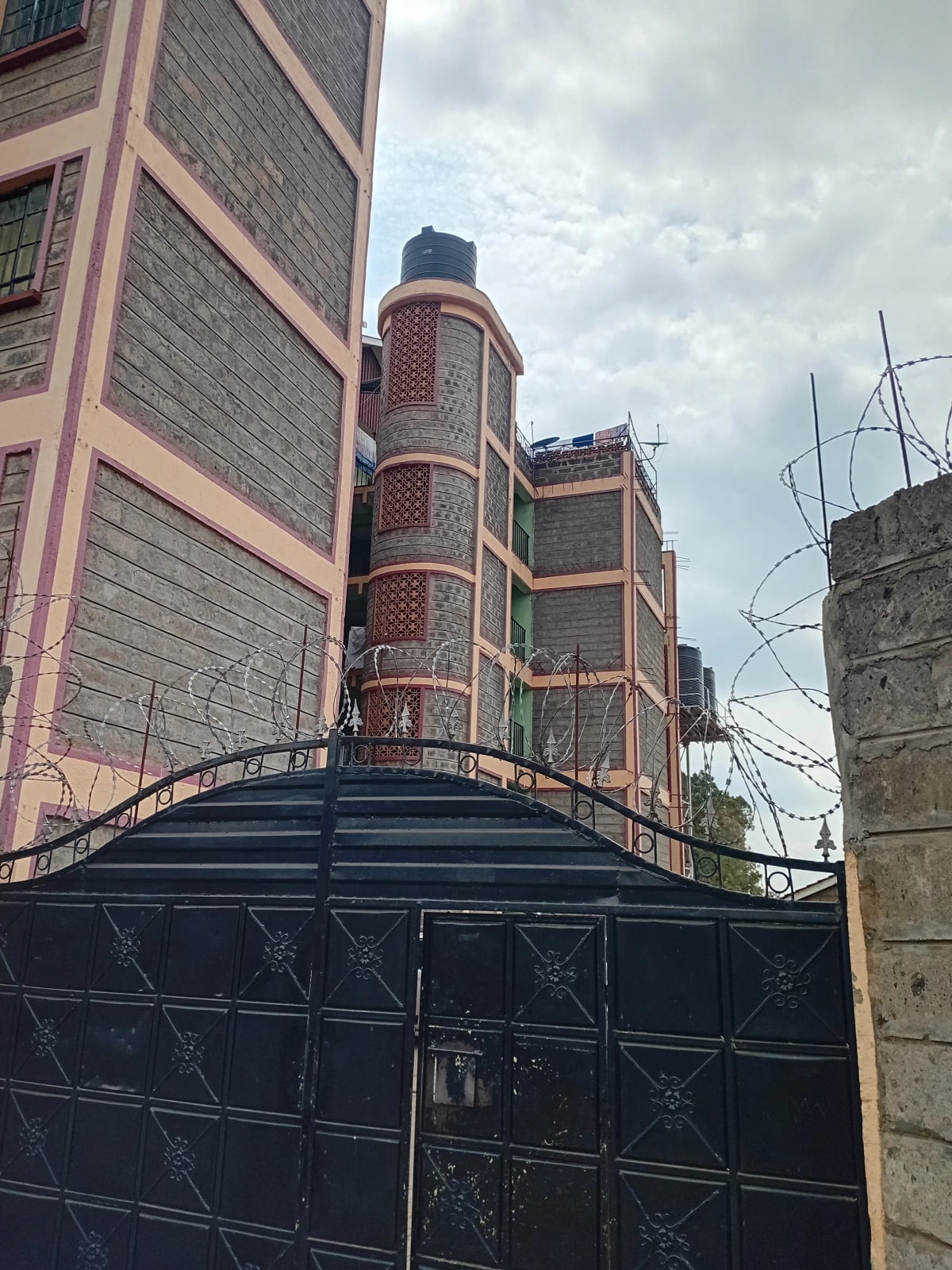 Black metal gate with multi-story brick building backdrop