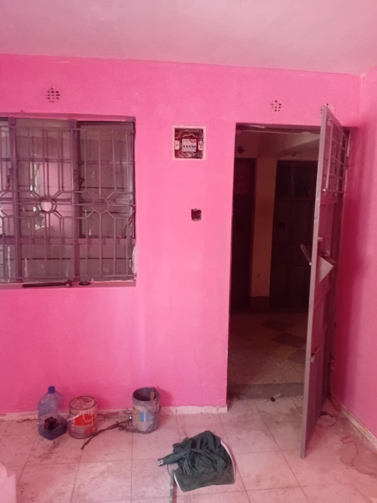 Pink painted room with window, door, and construction materials scattered