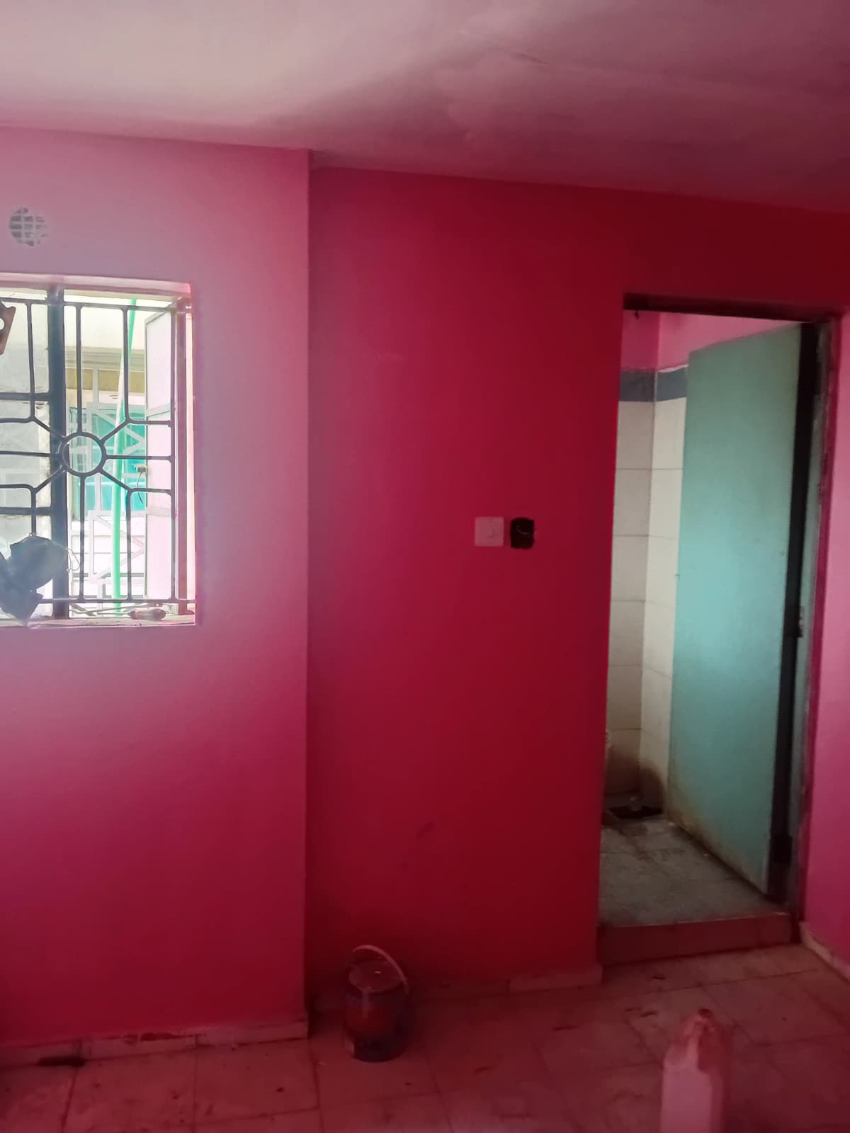Bright pink bedroom with barred window and open doorway