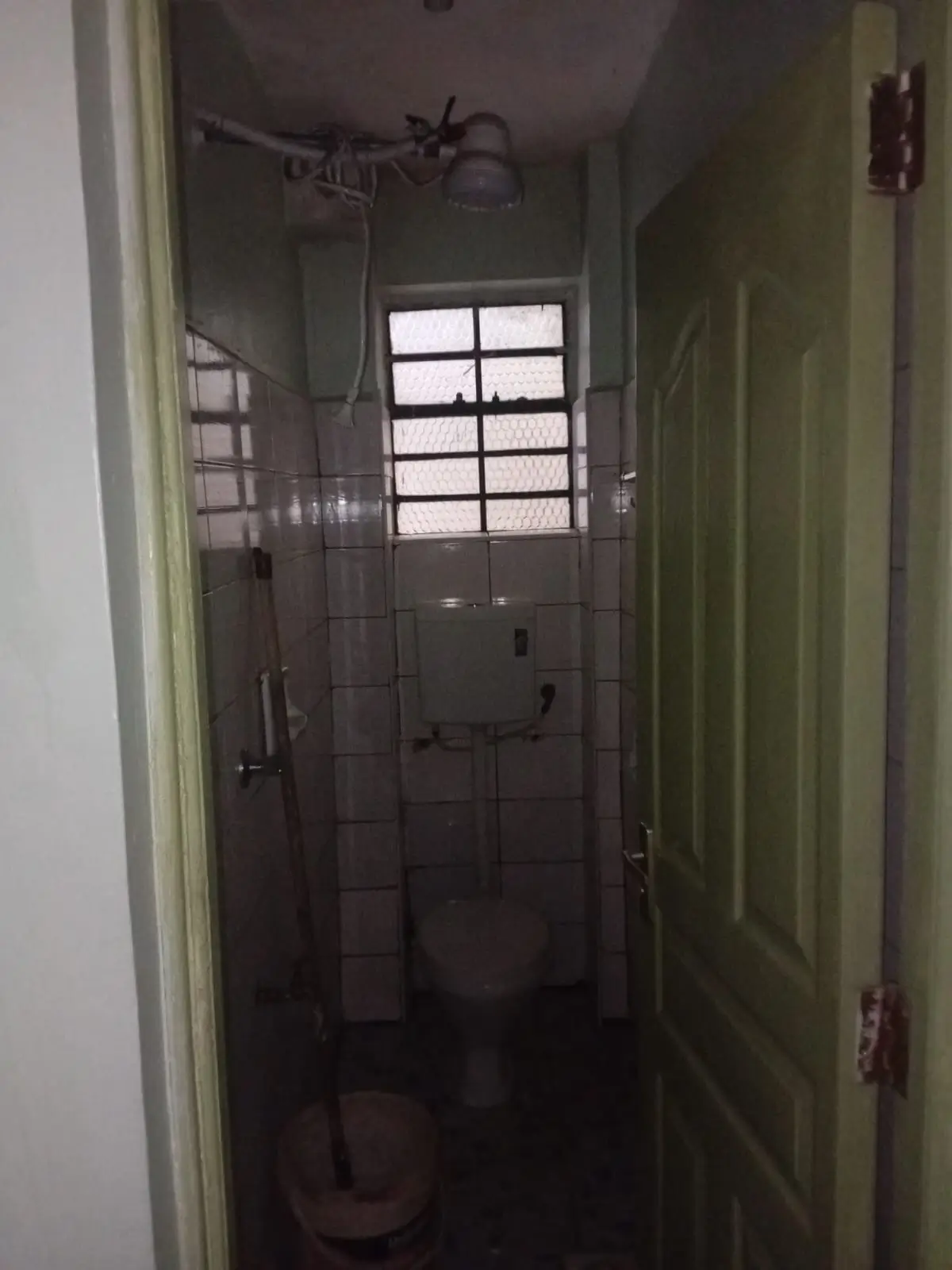 Narrow bathroom with toilet, shower area, tiled walls